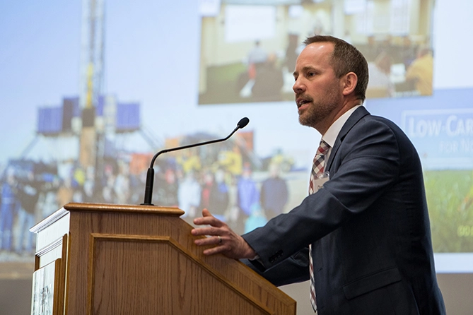 A man in a suit, speaking at a podium.