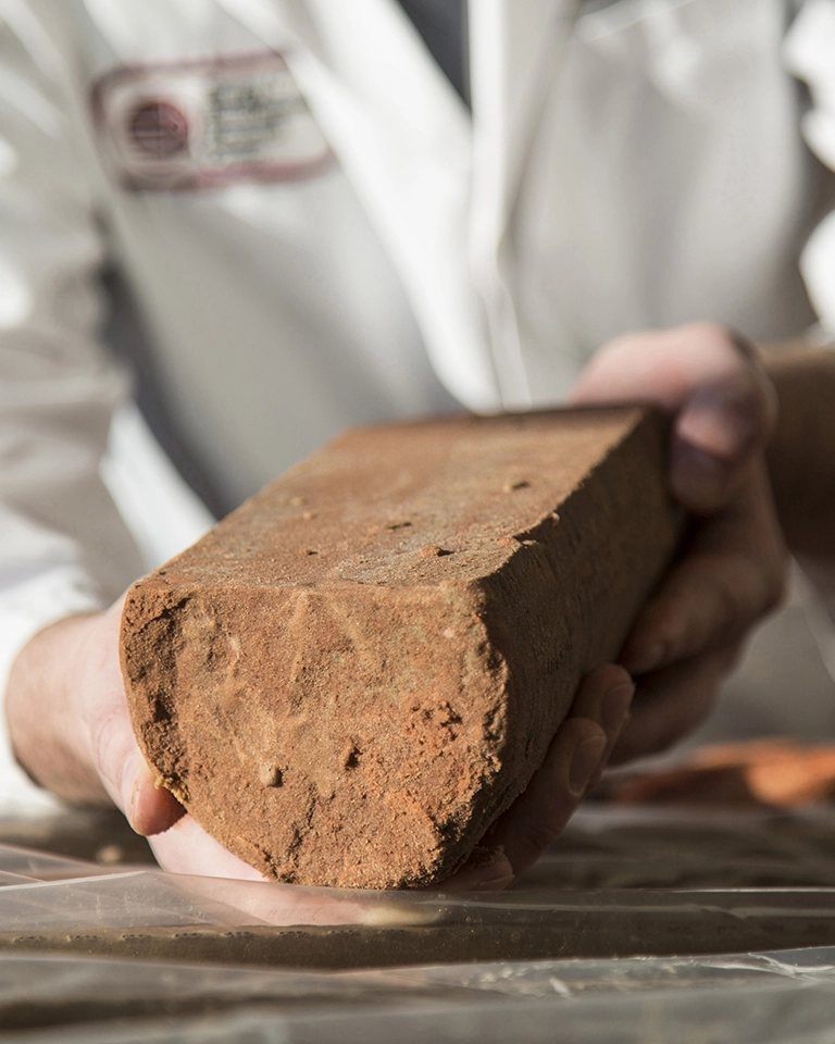 A person in a lab coat, holding a piece of sandstone