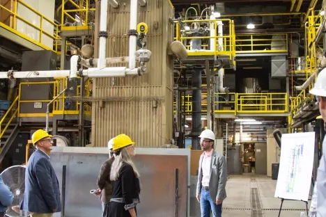 People in yellow and white hard hats standing in a pilot plant.