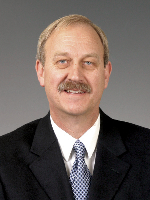 Dr. Michael Jones wearing a black suit and blue tie