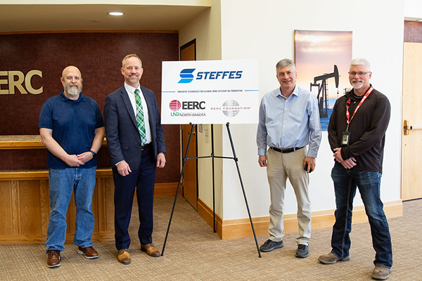 4 men posing for a photo around a poster with Steffes, EERC, and EERC Foundation logos on it.